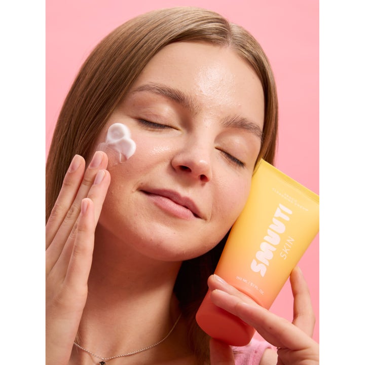 Smuuti Skin Peach Cleansing Cream 150 ml ansiktsrens kvinne påfører hvit krem fra en ferskenfarget tube