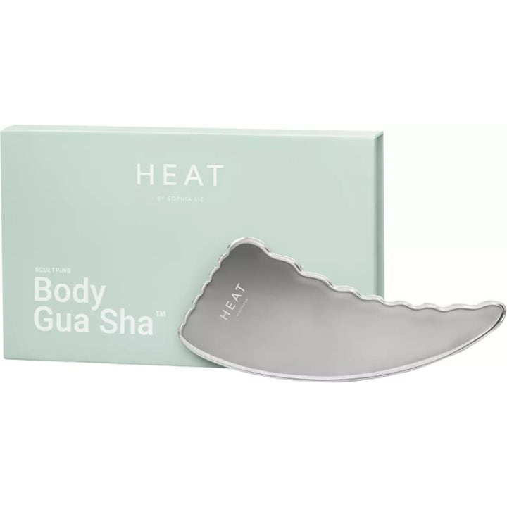 HEAT by Sophia Lie Body Gua Sha 1 stk i sølvfarget metall ved siden av lys grønn emballasje