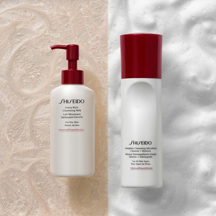 Shiseido Complete Cleansing Microfoam 180 ml ansiktsrens i hvit flaske med rødt lokk plassert på fyldig hvitt skum