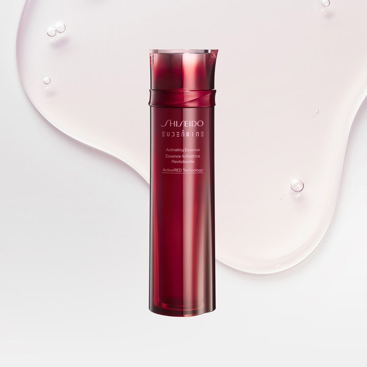 Shiseido Defend Eudermine Activating Essence 150 ml ansiktsvann i rød flaske plassert på en rosa dråpe tekstur