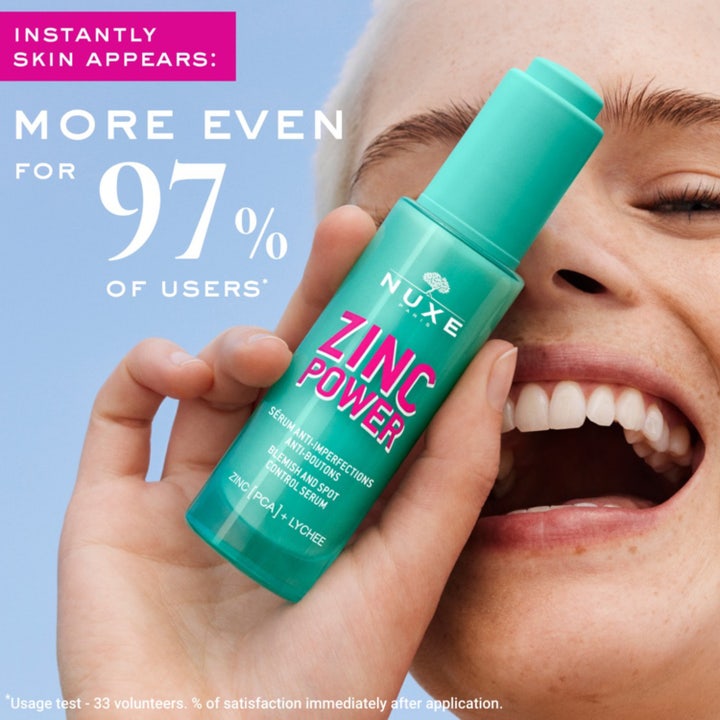 Nuxe Zinc Power Serum 30 ml mot urenheter i turkis glassflaske med pipette over en glitrende bakgrunn
