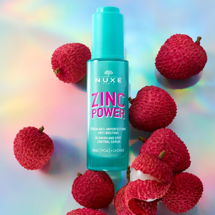 Nuxe Zinc Power Blemish And Spot Control Serum 30 ml mot urenheter i turkis flaske omgitt av rød litchi