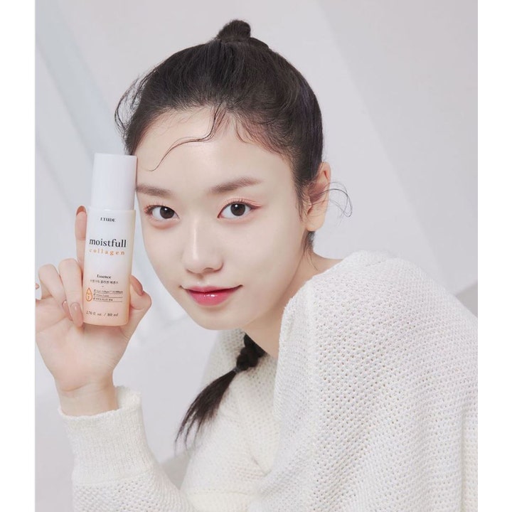 Etude Moistfull Collagen Essence 80 ml fuktighetsgivende serum i ferskenfarget flaske holdt av en kvinne.