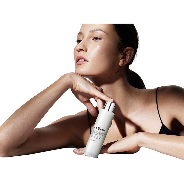 Elemis Dynamic Resurfacing Skin Smoothing Essence 100 ml utjevnende essence holdt av kvinne med glødende hud.