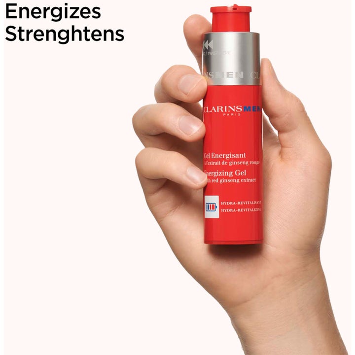 Clarins Clarins Men Energizing Gel 50 ml styrkende ansiktskrem med rød ginseng i rød flaske holdt i en hånd.