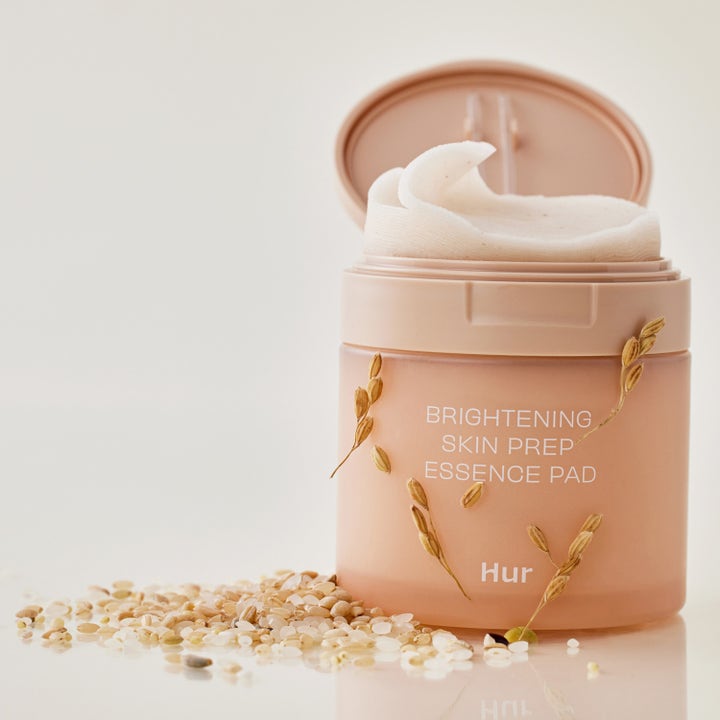 House of Hur Brightening Skin Prep Essence Pad 140 ml gir glød i en åpen beige krukke med hvite pads og dekorative riskorn.