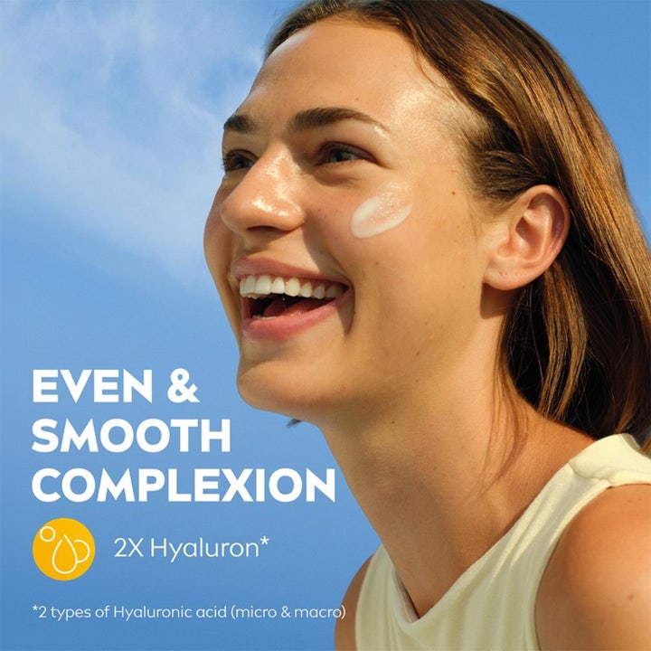 NIVEA Sun UV Face 2in1 Daily Serum 30 ml solkrem gir jevn hudtone vist på en smilende kvinne med serum på kinnet.