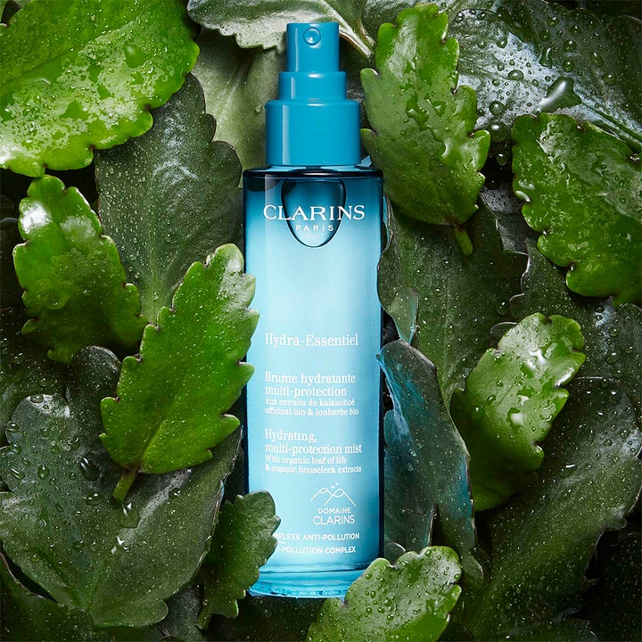 Clarins Hydra-Essentiel 75 ml fuktgivende ansiktsspray i blå glassflaske omgitt av grønne blader