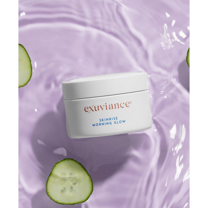 Exuviance SkinRise Morning Glow 36 stk ansiktsserum som gir glød i hvit krukke omgitt av lilla vann og agurk