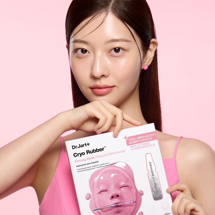 Dr.Jart+ Cryo Rubber Firming Mask 36 g ansiktsmaske med peptider som gir glød vist holdt av kvinne mot rosa bakgrunn.