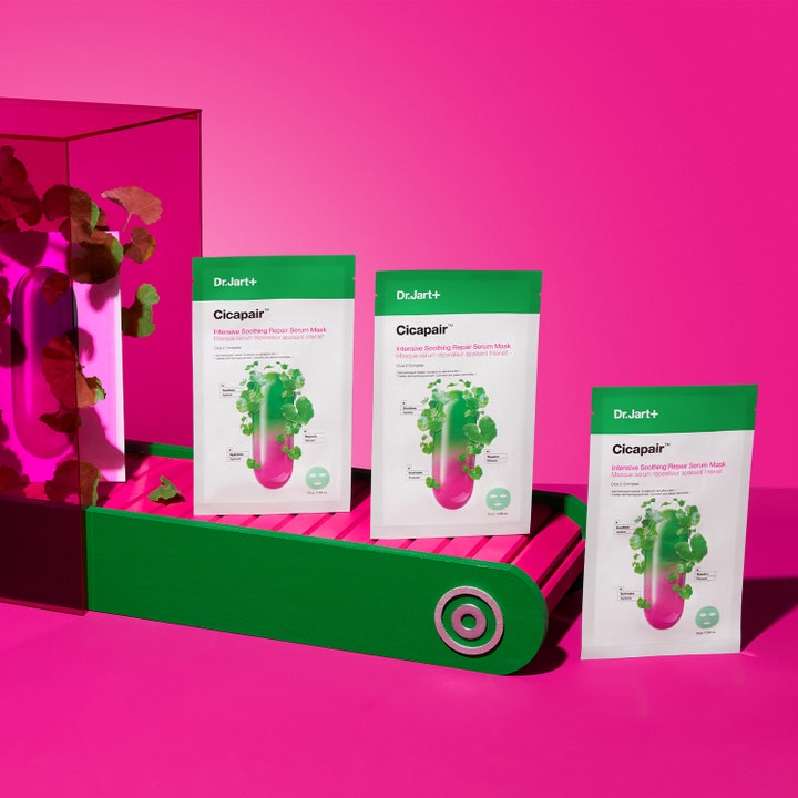 Dr.Jart+ Cicapair Intensive Soothing Repair Serum Mask 25 g beroligende arkmaske stilt opp på en grønn og rosa plattform.