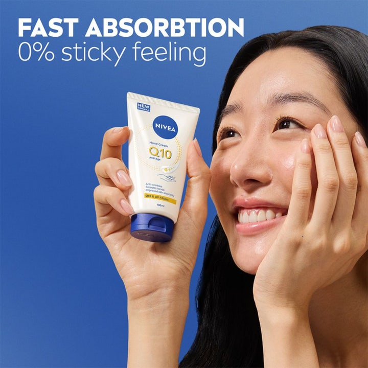 NIVEA Q10 Hand Cream 100 ml anti-age håndkrem som gir myk hud holdt av smilende kvinne mot blå bakgrunn