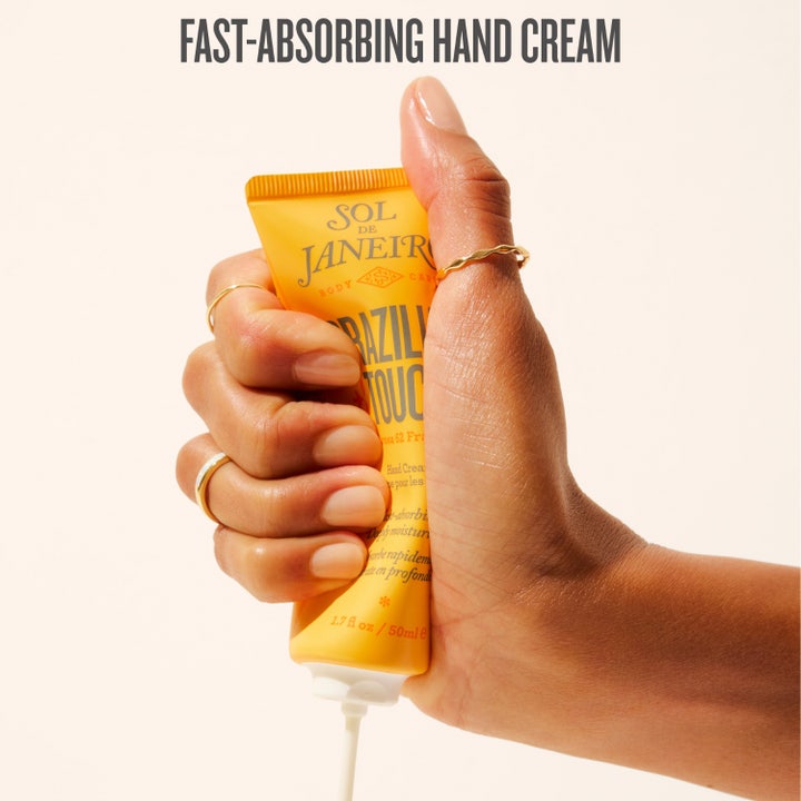 Sol de Janeiro Brazilian Touch Hand Cream 50 ml fuktighetsgivende håndkrem i gul tube holdt av fire hender.