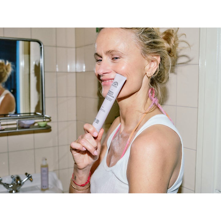 Rudolph Care Firming Therapy Moisturizer 50 ml oppstrammende dagkrem i lilla tube holdt av kvinne i baderomsmiljø