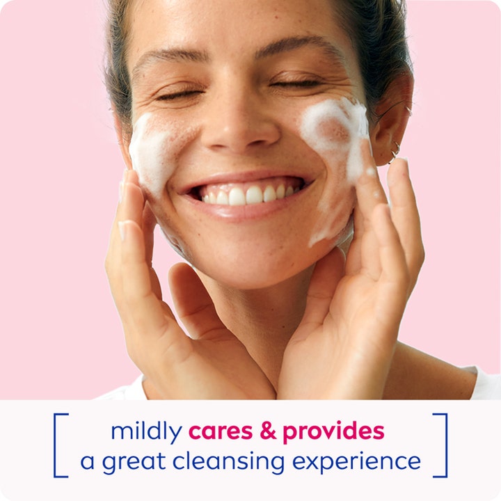 NIVEA Cleansing Mousse Caring 150 ml mildt rengjøringsskum påført av smilende kvinne med hvitt skum på kinnene.