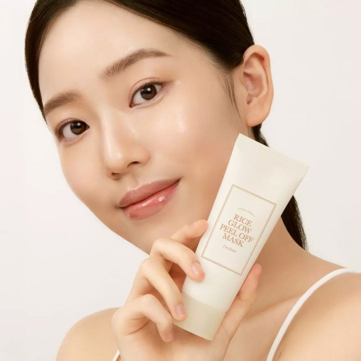 I'm from Rice Glow Peel Off Mask 70 g peelingmaske som gir glød vist av en kvinne som holder den hvite tuben